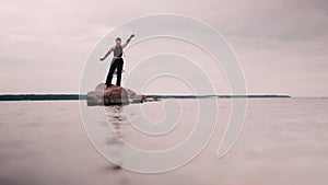 contemporary dancer in black clothes dancing on the rock in the sea