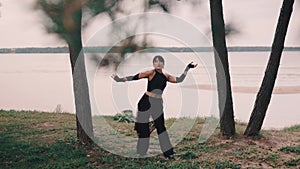 contemporary dancer in black clothes dancing among the trees by the sea