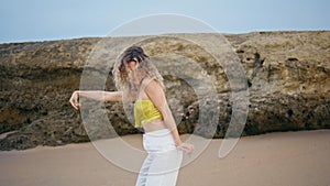 Contemporary dancer performing improvisation on sand summer day. Woman dancing