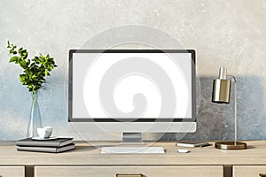 Contemporary designer desktop with empty white computer monitor, lamp, supplies and other items. Concrete wall background. Mock up