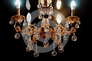 Contemporary glass chandelier isolated over black background. Chandelier for interior of the living room. Gold decoration