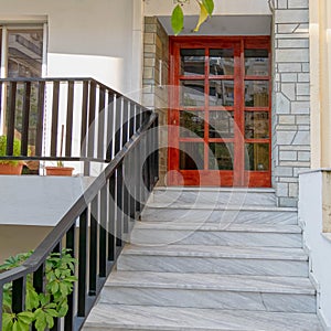 A contemporary house entrance with marble stairs to wood and glass door.