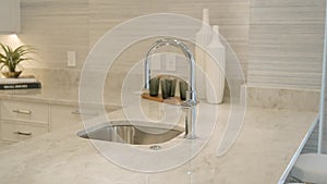 Contemporary kitchen area with polished chrome faucet and rectangular sink mounted on marble countertop. Decorative