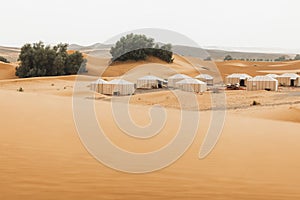 Contemporary luxury eco glamping camp Morocco Sahara desert. Sand dunes around