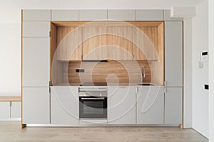 Contemporary minimal kitchen at empty refurbished apartment. Wooden furniture and modern appliances