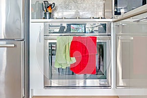 Contemporary, modern chrome stove and oven range, with color screen clock, and green and red dish towels hanging on the oven