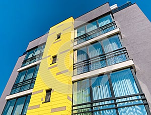 Contemporary residential building with yellow and gray panels exterior.