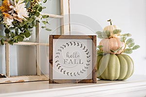 Contemporary stacked pumpkins on the mantel with a sign that say