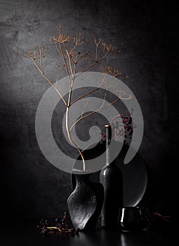 Contemporary still life with black vases and casual plants against a dark background