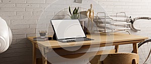 Contemporary working space in living room apartment, white brick wall, wood table, tablet blank screen