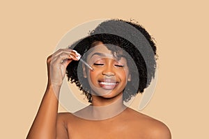 Content black woman applying serum, skincare ritual