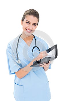 Content brown haired nurse in blue scrubs filling an agenda