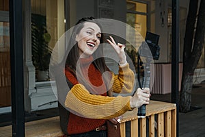 Content creator, blogger, vlogger young woman taking selfies, filming herself and having fun on city street.