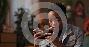 Content creator online influencerAfrican woman in the living room holds her cellphone horizontally, immersed in a live