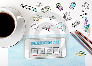 Content Management System concept. Mobile phone and coffee cup on a white office desk