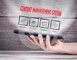 Content Management System concept. Tablet computer in the hand. Old wooden background