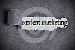 Content marketing word under torn black sugar paper