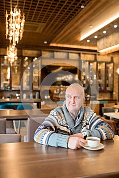 Content mature man drinking coffee in cafe