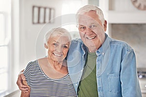 Content senior couple standing together at home in their kitchen