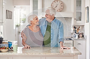 Content seniors standing in each other`s arms together at home