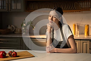 Content Woman in Apron Resting in Sunlit Kitchen With Fresh Produce