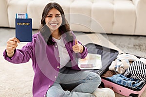 Content woman with passport giving thumbs up