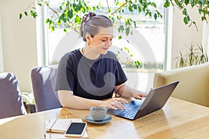 Content Woman Working on Laptop with Coffee in Cafe