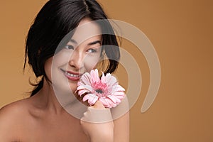 Content young Asian lady with fresh flower in hand smiling in studio