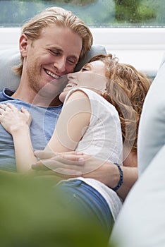 A content young couple happily snuggling while lying on the couch. A content young couple happily snuggling while lying