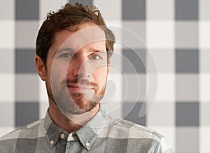 Content young man wearing a shirt matching his checkered wallpaper