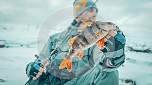 Contented angler holds in his hand a perch