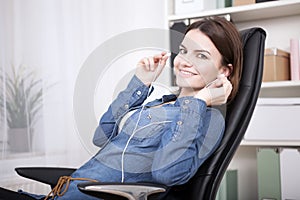 Contented businesswoman sitting listening to music