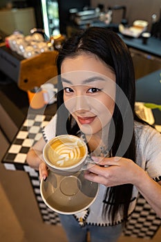 Contented cafe visitor holding a caffeinated beverage in her hand