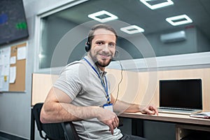 Contented man in headphones turning around at workplace