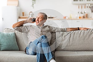 Contented Mature Man Talking On Cellphone Looking Aside At Home