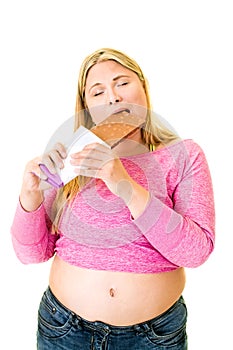 Contented obese woman eating large chocolate bar