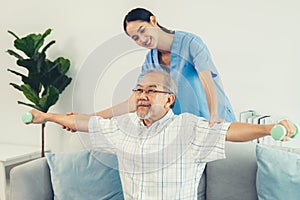 Contented senior patient doing physical therapy with the help of his caregiver.