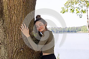 Contented young woman hugging a large tree with a blissful expression and her eyes closed in a concept of save the