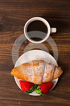 Continental breakfast with croissant, coffees and fresh strawberries.