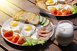 Continental breakfast set of eggs, ham, vegetables and cheese. Bread and coffee on a wooden table. Breakfast for two