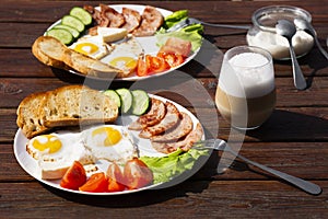 Continental breakfast set of eggs, ham, vegetables and cheese. Bread and coffee on a wooden table. Breakfast for two