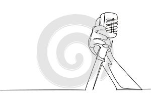Continuous one line drawing hand holding a retro microphone over white background. Rock music live concert with old microphone.