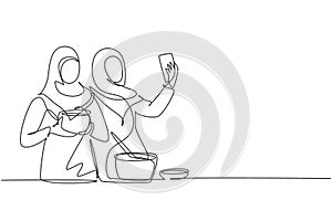 Continuous one line drawing two Arab woman taking selfie or making video call using her smartphone while cooking fresh salad.