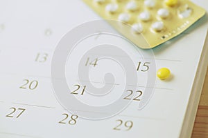 Contraceptive control pills on date of calendar background.
