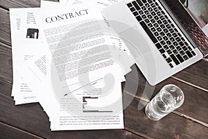 Contract documents and laptop computer on wooden tabletop