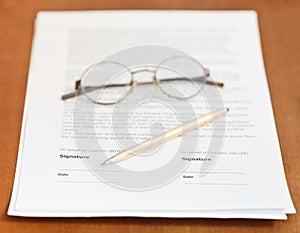 Contract, golden pen and eyeglasses on table