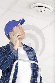 Contractor by air vent talking on smartphone