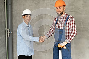 Contractor and client shaking hands with team builder in renovation site. Partnership, contractor