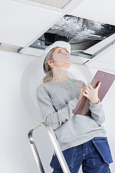 Contractor with clipboard looking into roofspace