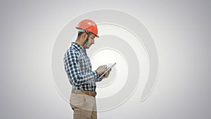 Contractor engineer in hardhat inspecting construction site holding digital tablet on white background.